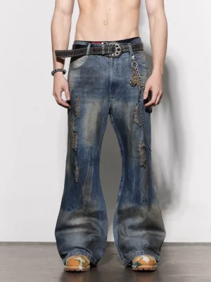 Front view of distressed rusty blue wash flare jeans with ripped frayed denim details styled with a studded belt and metal pant chain