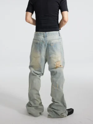 Back view of men's distressed vintage washed blue flare jeans with rear patch pockets, belt loops, faded worn areas, ripped leg details, and long stacked flared hems