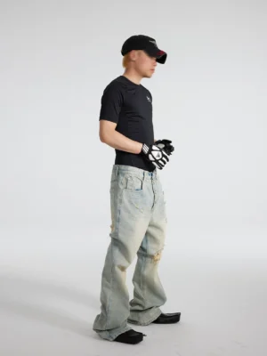 Men's distressed vintage blue sunfade flare jeans shown in a right side full-body studio view, featuring a relaxed thigh, ripped knee details, faded denim wash, and stacked wide hem