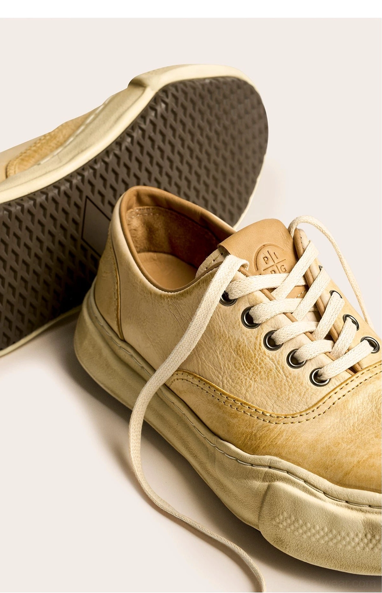 Side view of distressed tan leather sneakers showing the exposed thick sole, waffle anti-slip tread, washed upper, and leather insole