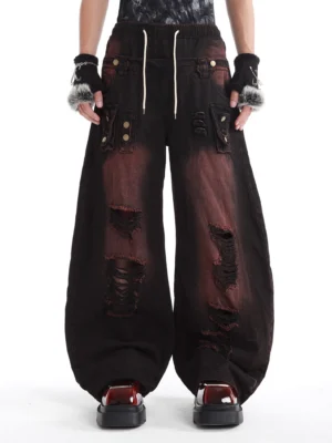 Front view of distressed two-tone wide-leg cargo denim pants with ripped details oversized utility pockets and drawstring waist
