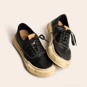 Black distressed washed leather retro sneakers shown from an oblique top-down angle with thick aged off-white dissolved soles and classic lace-up design