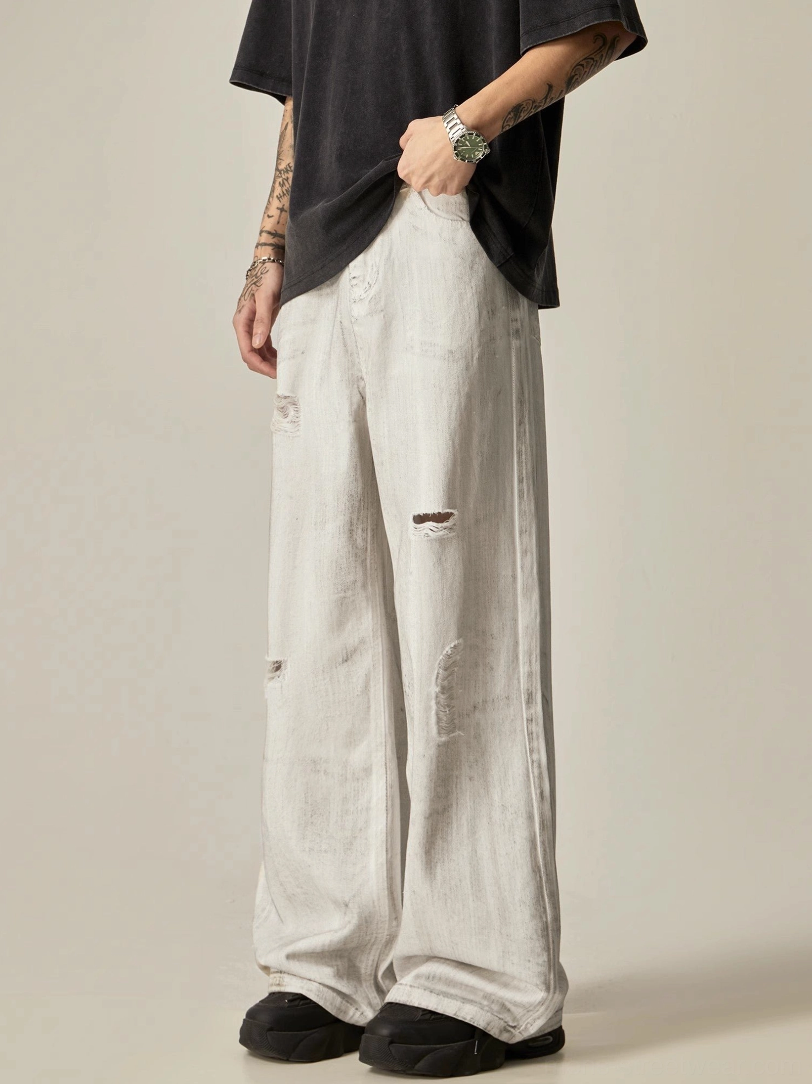 Three-quarter side view of distressed white wide-leg jeans showing ripped denim and loose silhouette