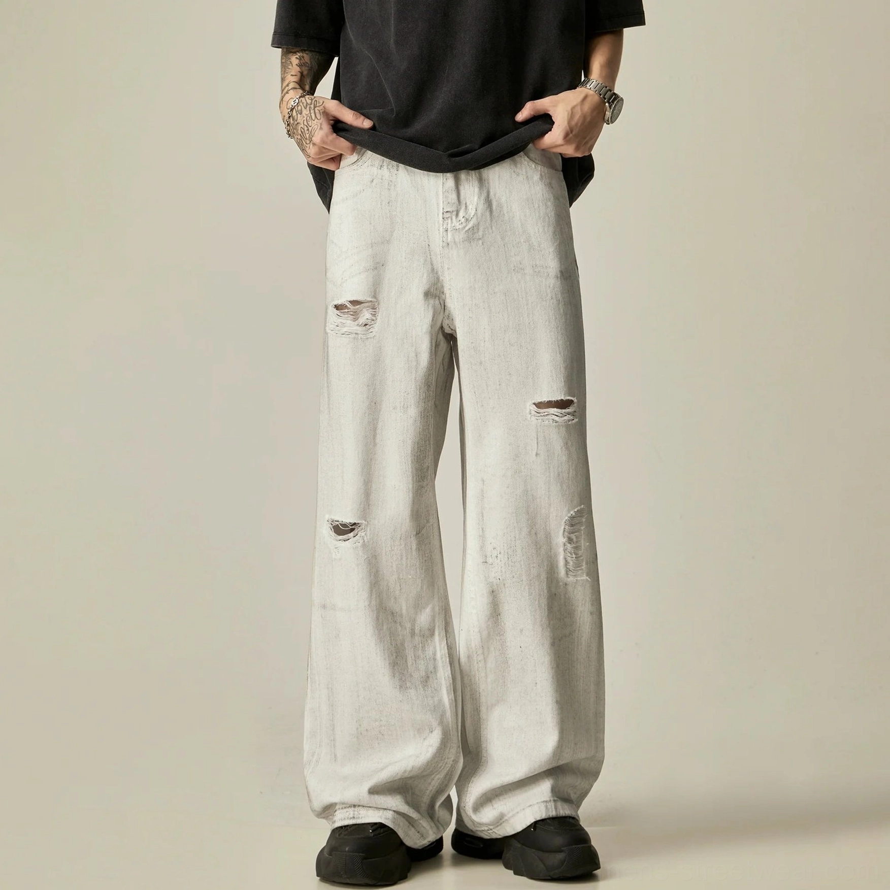 Close front view of distressed white wide-leg streetwear jeans styled with black t-shirt and shoes