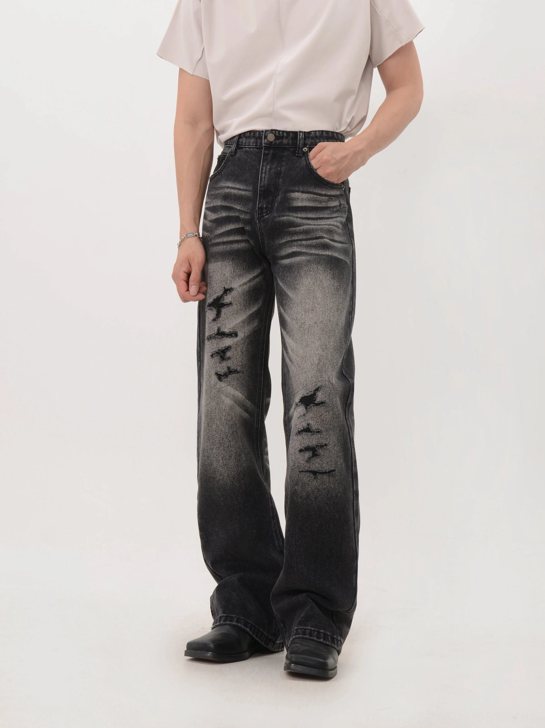 Faded charcoal black distressed wide-leg denim jeans with gradient wash in angled streetwear view