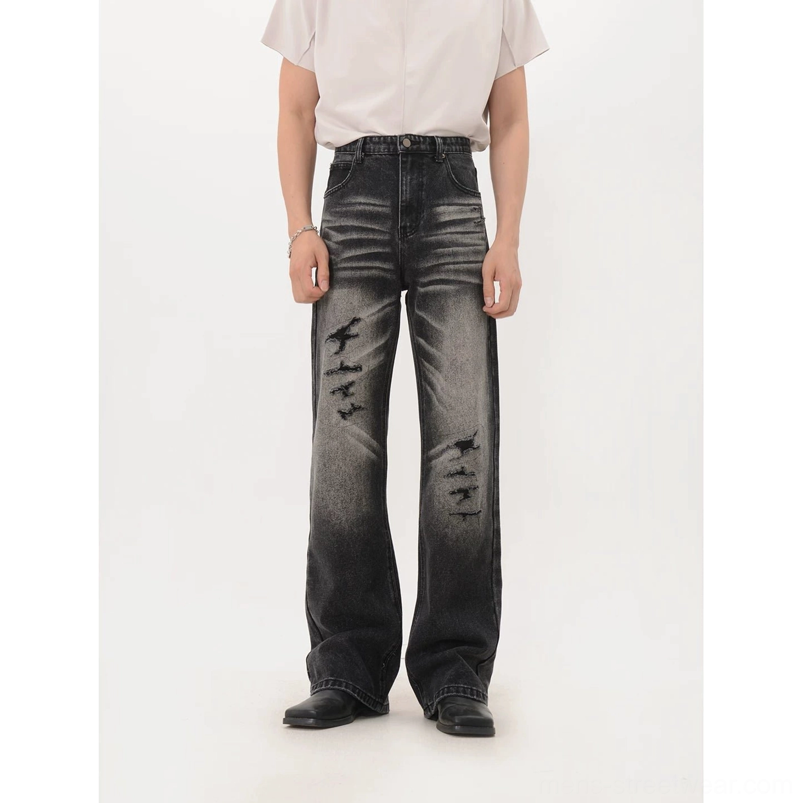 Faded black distressed wide-leg denim jeans with ripped front details and loose streetwear silhouette