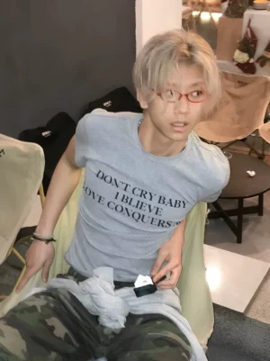 Light gray Don’t Cry Baby slogan T-shirt with black serif graphic print styled on a model in a casual streetwear setting