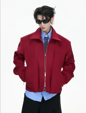 Front full-body view of a structured double-zip sculpted cropped wool jacket styled with a blue shirt striped tie and black sunglasses