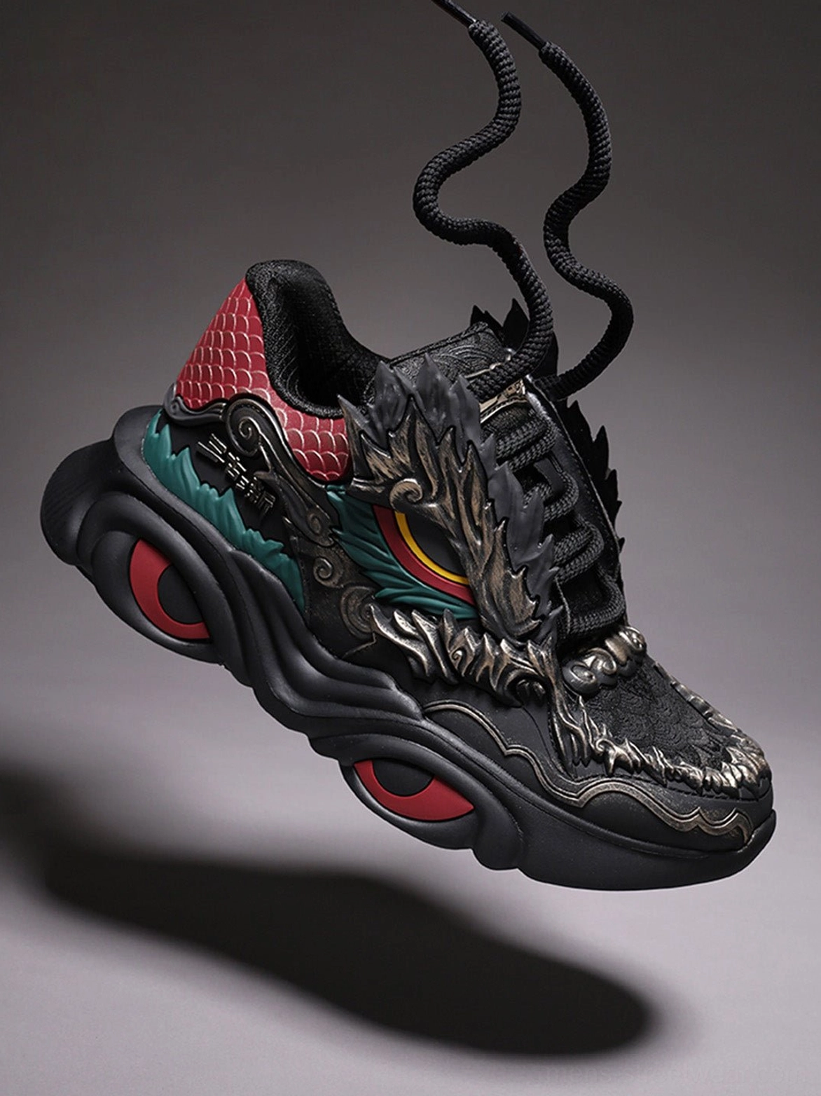 Front angled black dragon crest chunky runner sneaker with prominent dragon head vamp red heel detail and layered technical upper