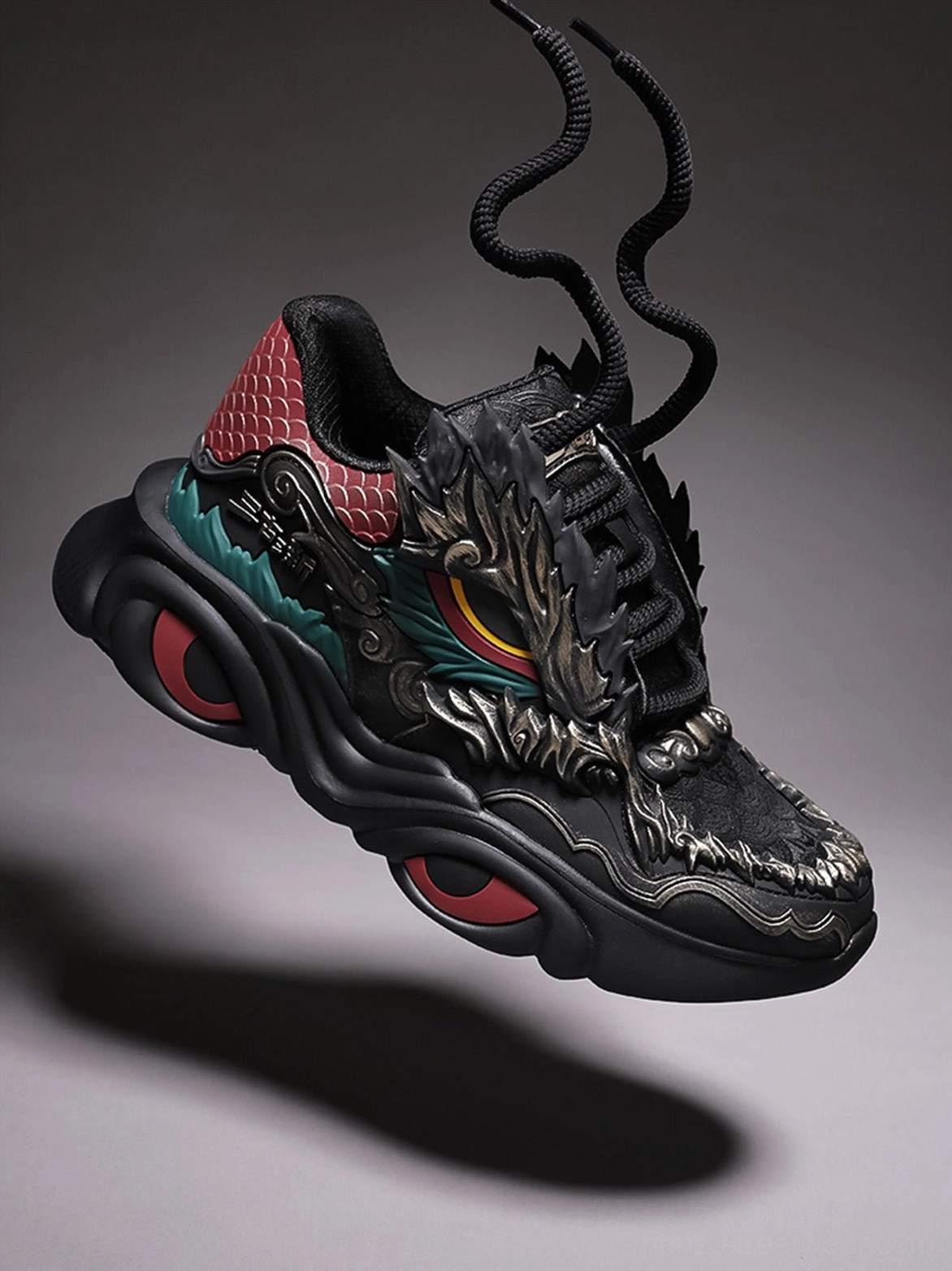 Front three quarter view of black dragon crest chunky runner sneaker with detailed dragon face vamp teal accent and raised outsole