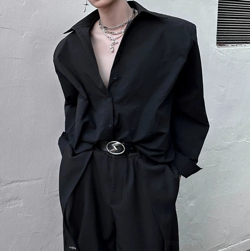 Close-up of black oversized cuff shirt with half-unbuttoned collar and structured relaxed streetwear silhouette