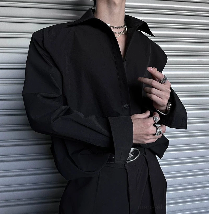 Black oversized streetwear shirt featuring wide folded cuffs, metal buckle belt, and contemporary accessories