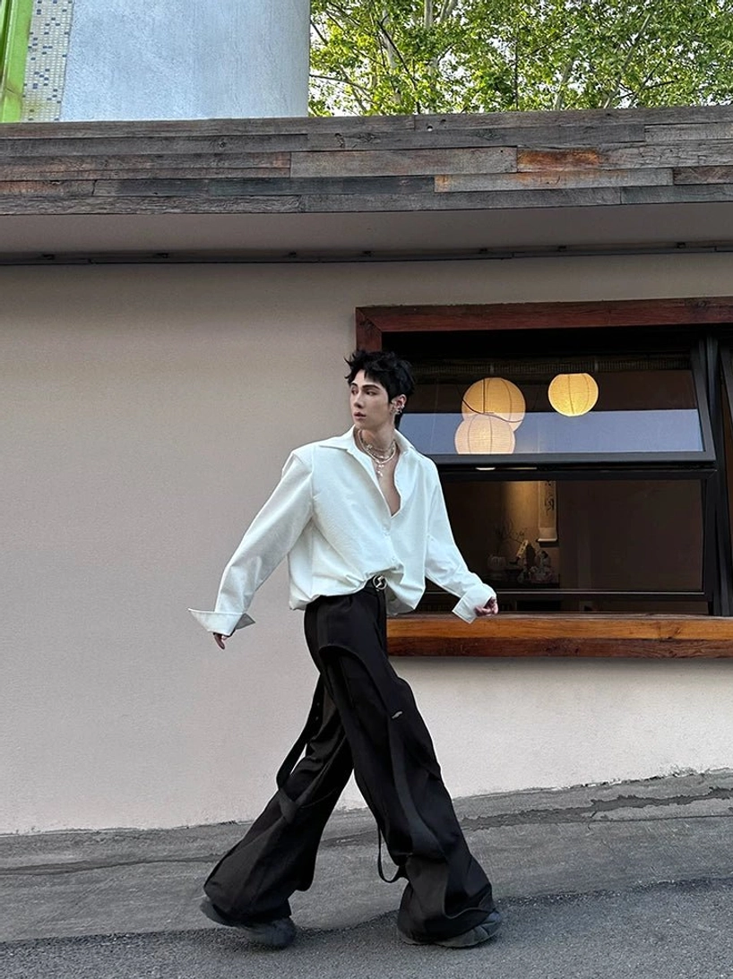 White oversized cuff shirt shown in motion with wide sleeves and high-waisted black wide-leg trousers