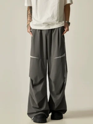 Dark gray dual-stripe wide-leg track pants shown from the front with curved white knee panels and a loose Seoul streetwear silhouette