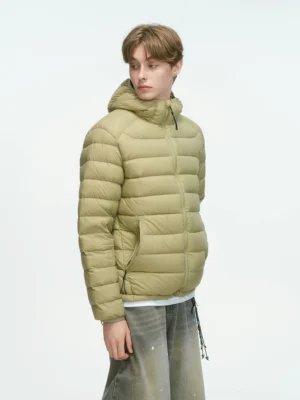 Khaki hooded quilted down puffer jacket shown in a three-quarter view with hand-warmer pockets, relaxed fit, and vintage baggy denim