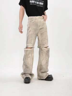 Front full body view of beige dune modular detachable stacked flare pants with split knee construction and washed streetwear finish