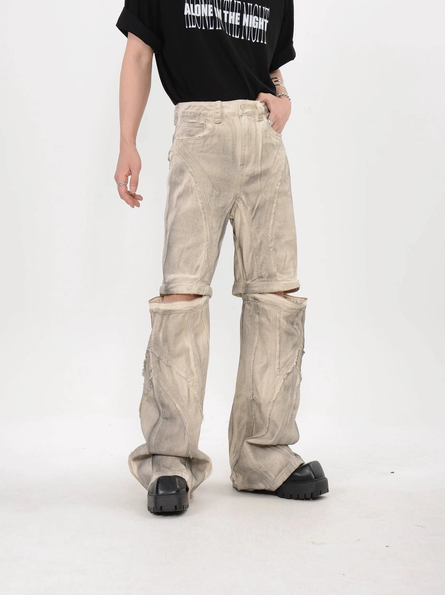 Side three quarter view of beige dune detachable stacked flare pants showing asymmetric split knee panel and layered lower leg