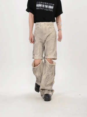 Three quarter walking view of beige convertible stacked flare pants with detachable lower leg panels and deconstructed seams