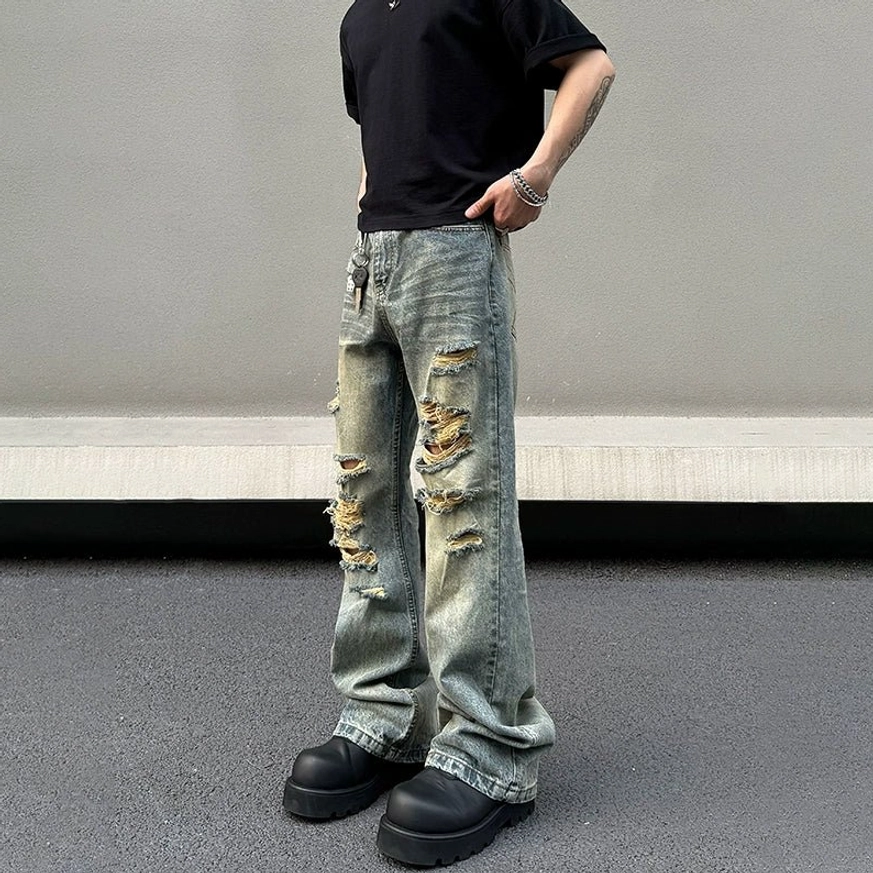 Front three quarter view of acid washed blue shredded flared jeans styled with black t shirt and platform boots