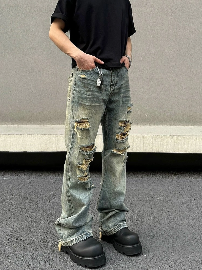 Front low angle view of blue distressed flared jeans with shredded rips raw frayed hems and platform boots