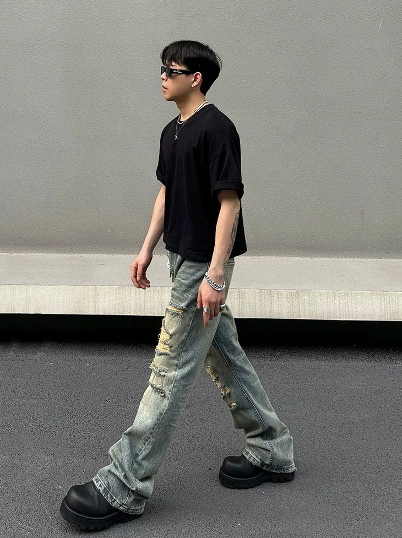 Side profile of vintage washed blue flared distressed jeans with ripped leg details and bootcut silhouette