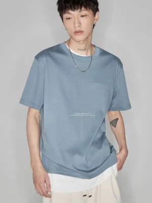 Dusty blue minimalist letter print crew neck tee front view upper body shot showing refined chest letter detail and relaxed fit silhouette