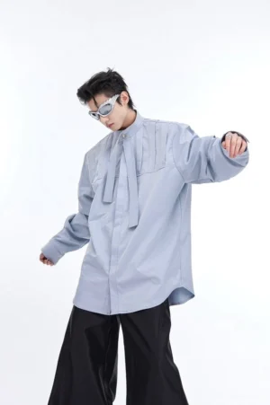 Dusty blue oversized pleated stand collar button-down shirt with neck tie shown in three-quarter studio view