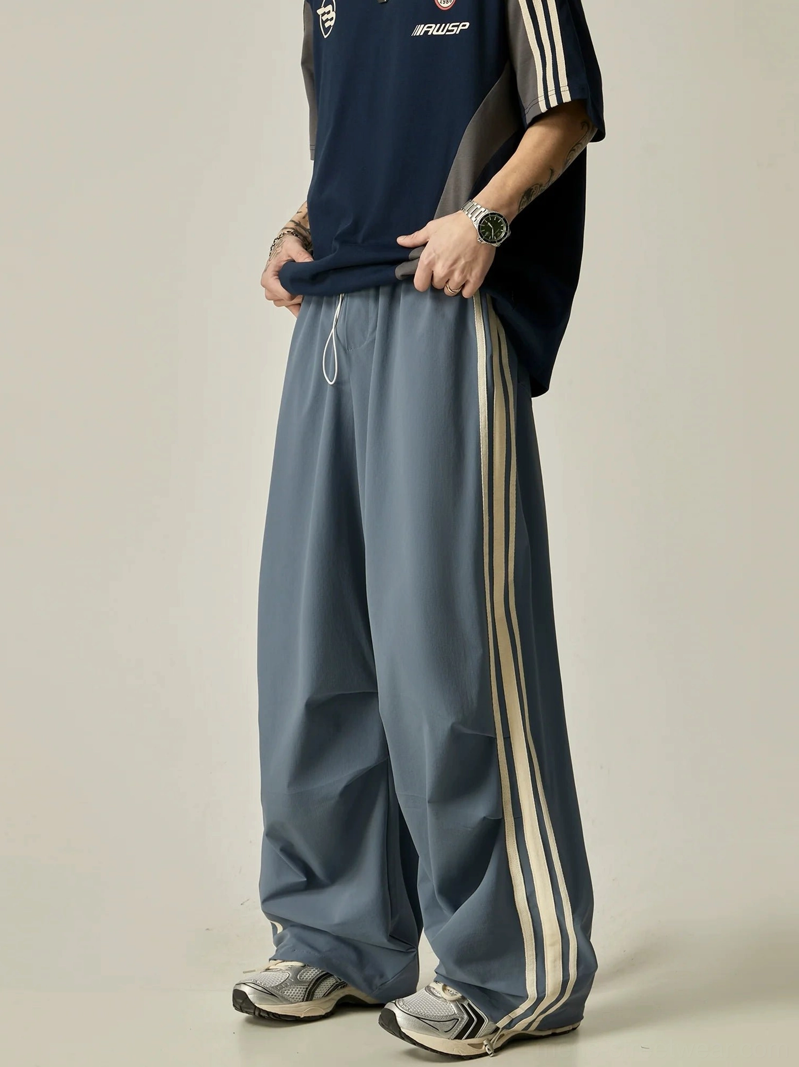 Dusty blue wide-leg triple stripe nylon track pants with off-white stripes and elastic drawstring waist front view