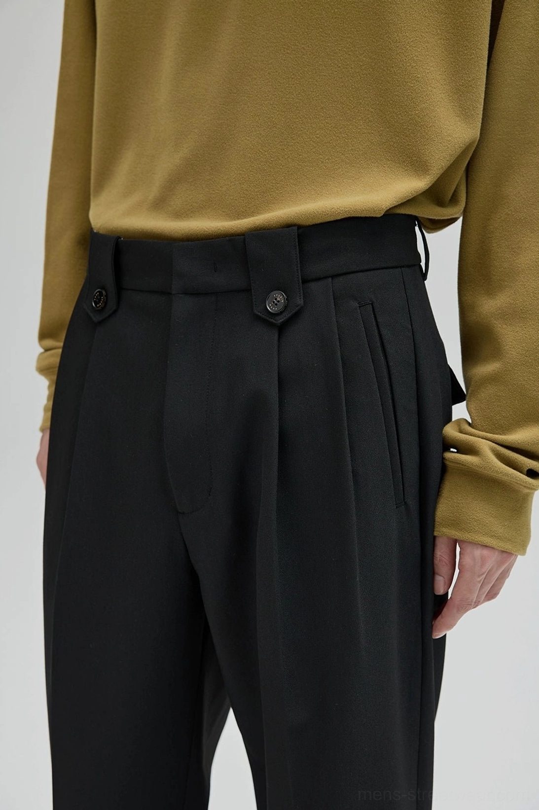 Close-up of black wide leg suit pants showing buttoned waist tabs front pleats and tailored stitching