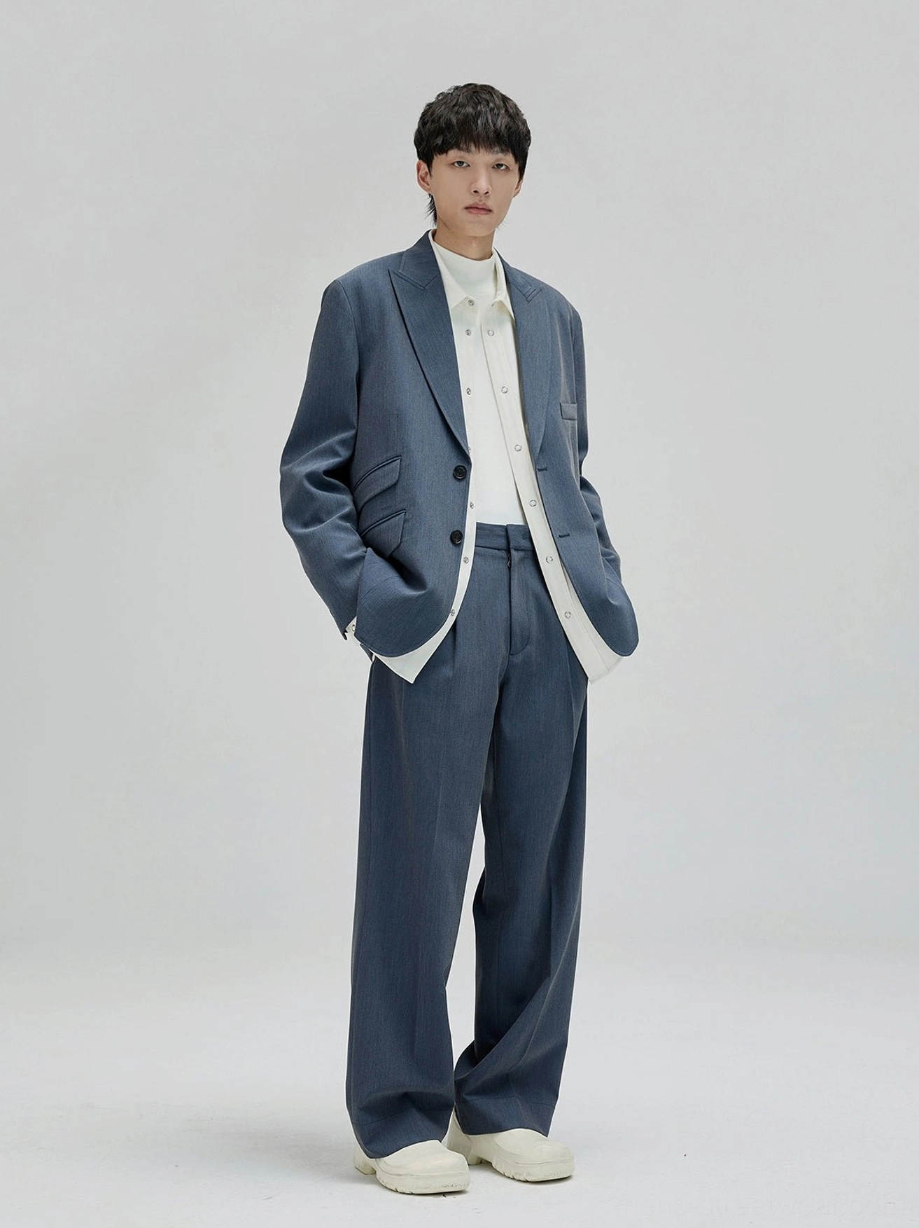 Dusty blue tailored suit with relaxed wide leg suit pants and layered white shirt in contemporary East Asian fashion