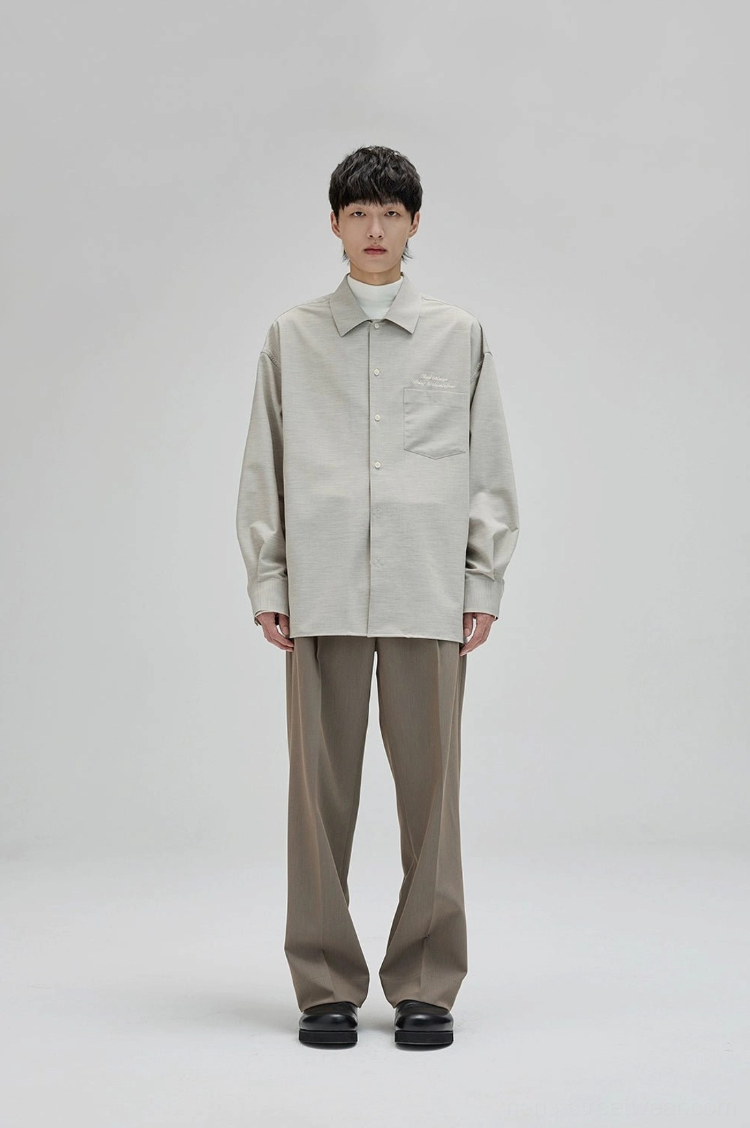 Relaxed pleated suit trousers with smooth drape and understated minimalist streetwear aesthetic