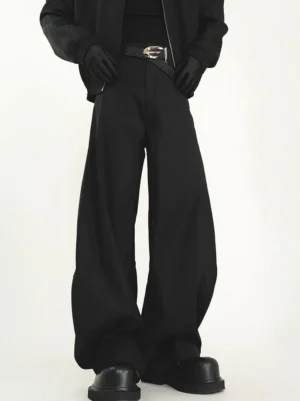 Close-up front view of black high-rise ultra wide-leg trousers with a metal buckle belt, cropped jacket, gloves, and black leather shoes