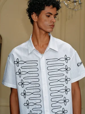 Front close-up of white pinstripe embroidered loop short sleeve shirt with black floral cord embroidery and sleeve accent