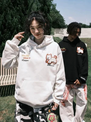 Black and off-white embroidered puppy graphic oversized streetwear hoodies worn by two models outdoors