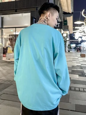 Cyan blue oversized long sleeve crew neck streetwear T-shirt shown from the rear on a male model at night
