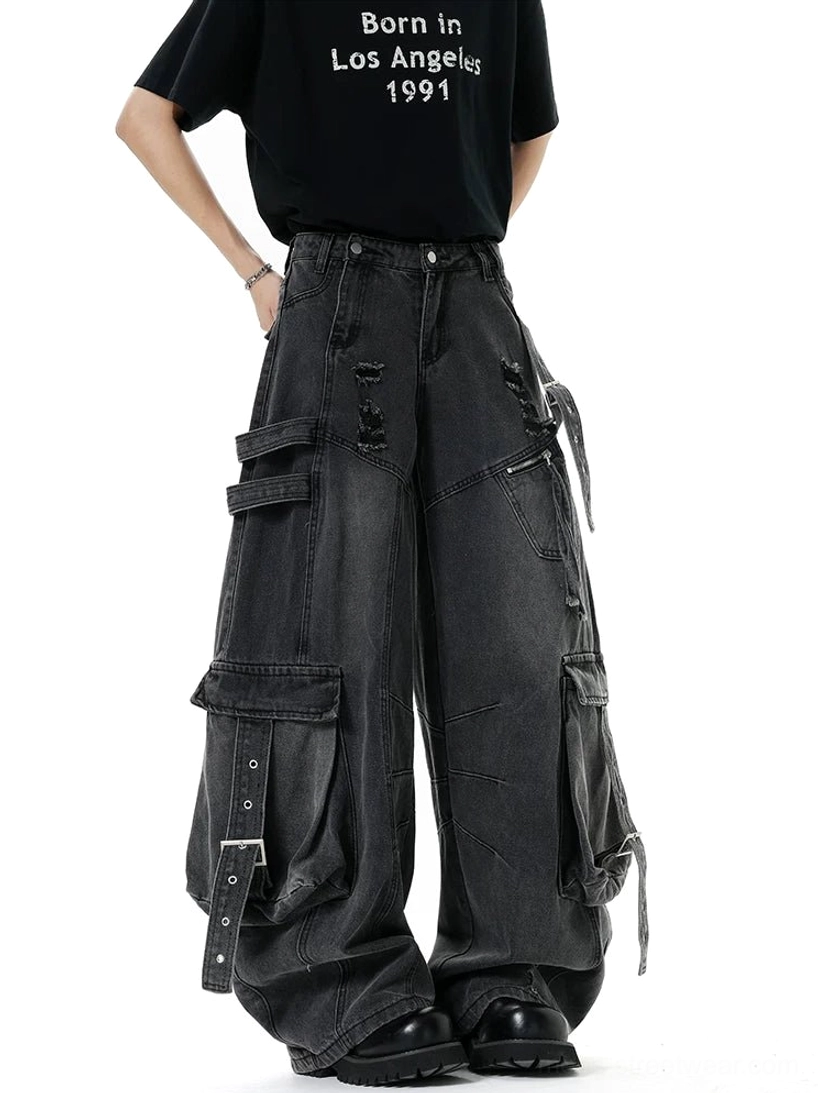 Faded black cargo denim pants with buckle-fastened pockets, distressed fraying, wide baggy legs, and dark Korean streetwear styling