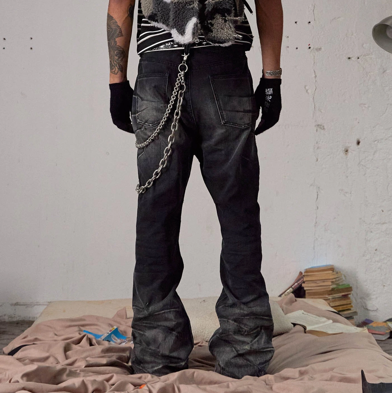 Rear view of faded black flared streetwear jeans featuring back pockets and double metal chain details