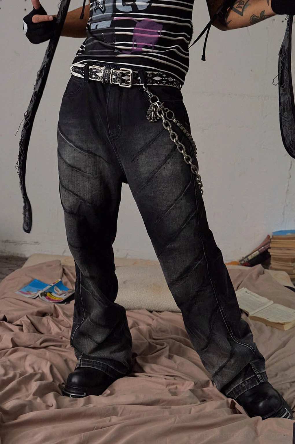 Close-up front view of faded black chain detail flared jeans showing diagonal panel seams and metal hardware