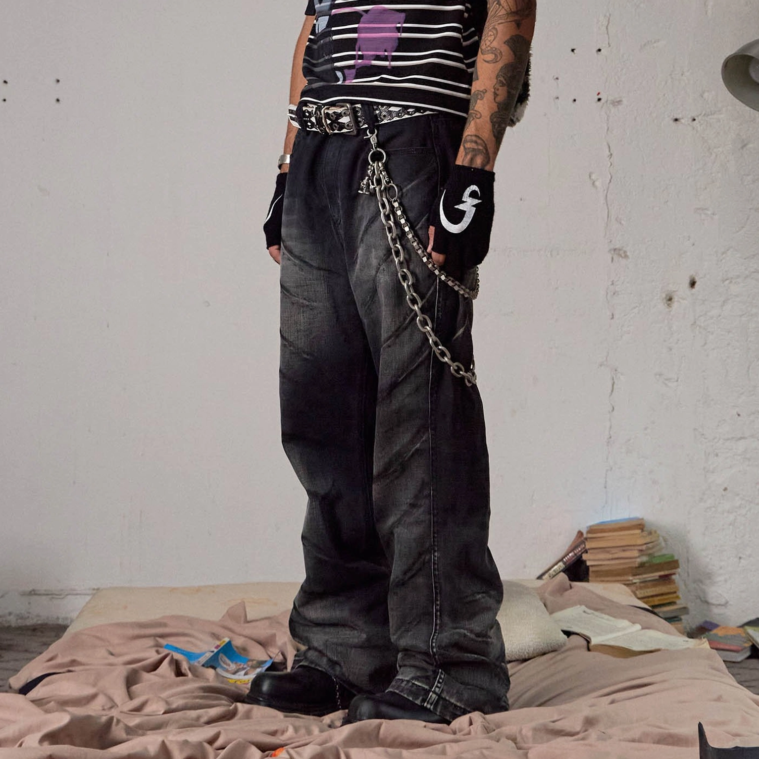 Side full-body view of faded black chain detail flared jeans with wide-leg silhouette and waist hardware