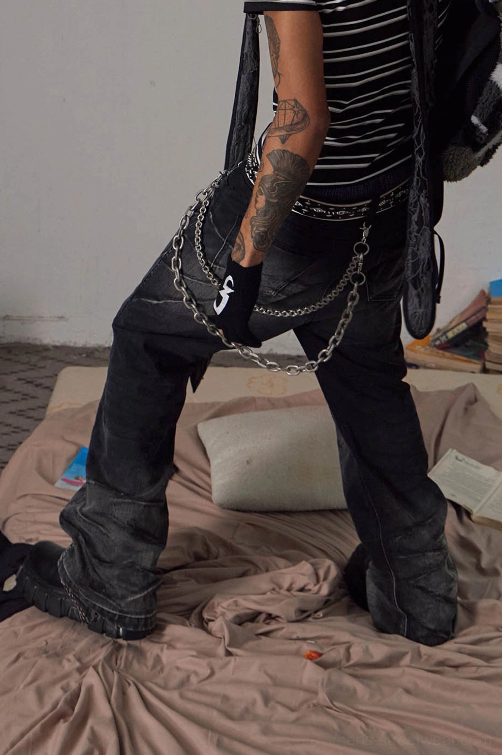 Side lower-body view of faded black chain detail flared jeans in a wide stance with layered metal chains