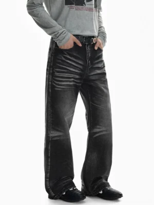 Three-quarter front view of faded black flare jeans with strong thigh whisker fading, relaxed wide-leg silhouette, belt loops, and stacked hem styled with a gray long-sleeve top and black shoes