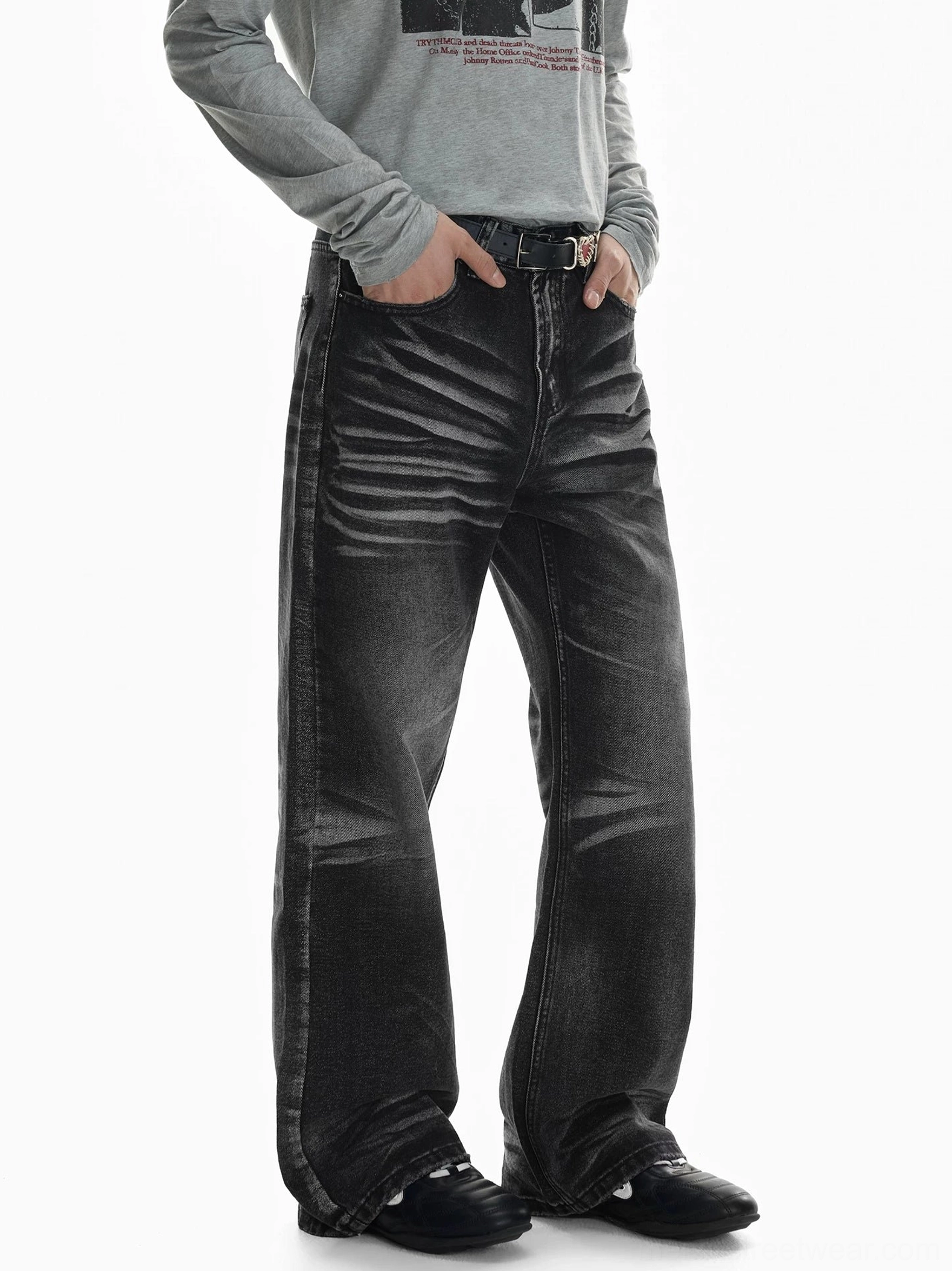 Three-quarter front view of faded black flare jeans with strong thigh whisker fading, relaxed wide-leg silhouette, belt loops, and stacked hem styled with a gray long-sleeve top and black shoes
