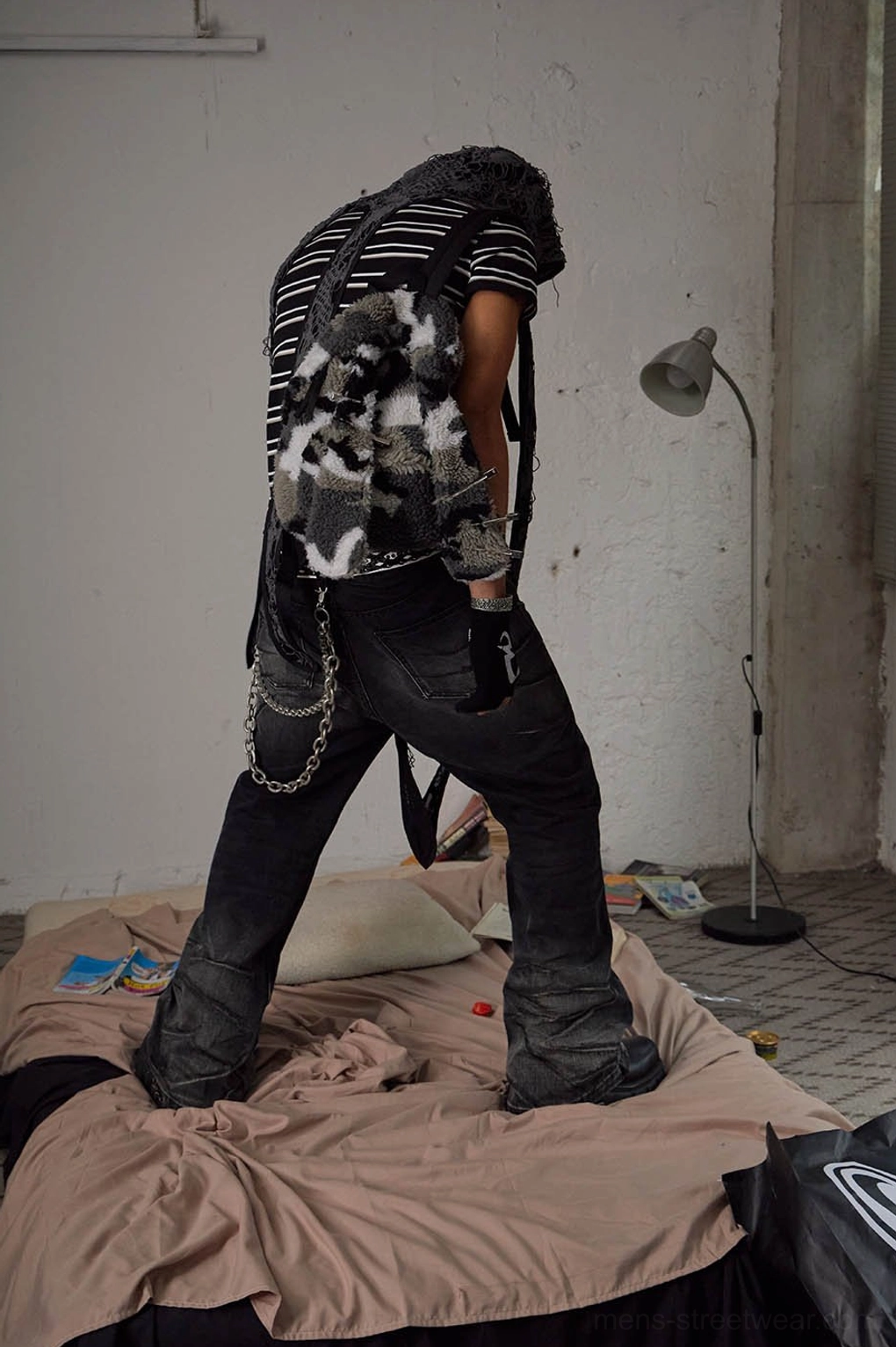 Rear three-quarter view of faded black flared jeans with multiple silver-tone chains and distressed streetwear wash