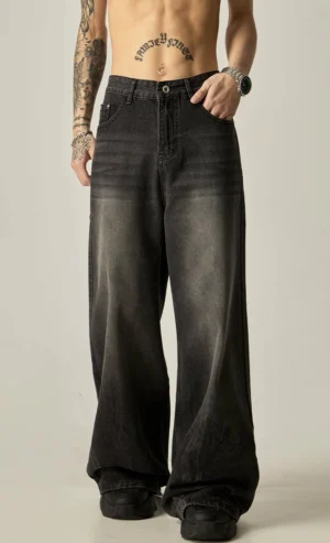 Front view of faded black wide-leg denim jeans with button zip closure, relaxed high-rise waist, washed gradient finish, and black chunky shoes