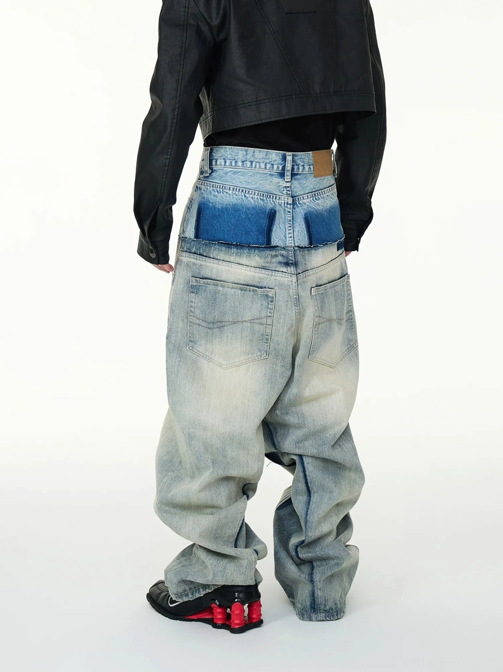 Rear view of faded blue layered baggy jeans showing the double waist panel classic back pockets and stacked denim hem