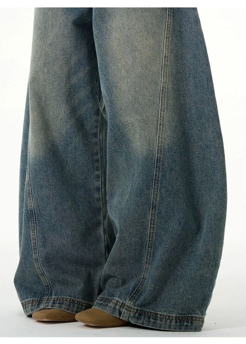Low-angle close-up of faded vintage blue wide-leg jeans showing wide hems and structured side seams