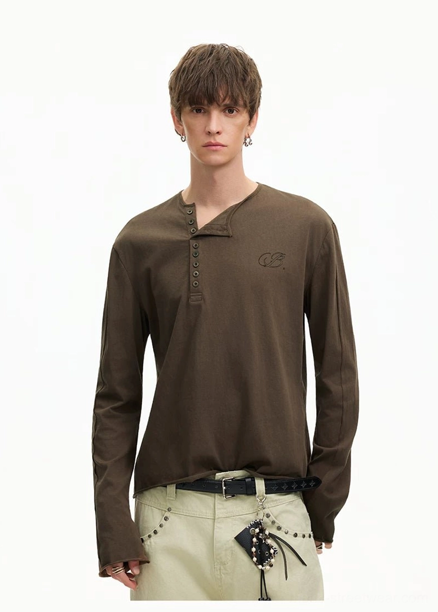 Front view of a faded cotton brown Henley T-shirt styled with khaki pants, black belt, and layered streetwear accessories