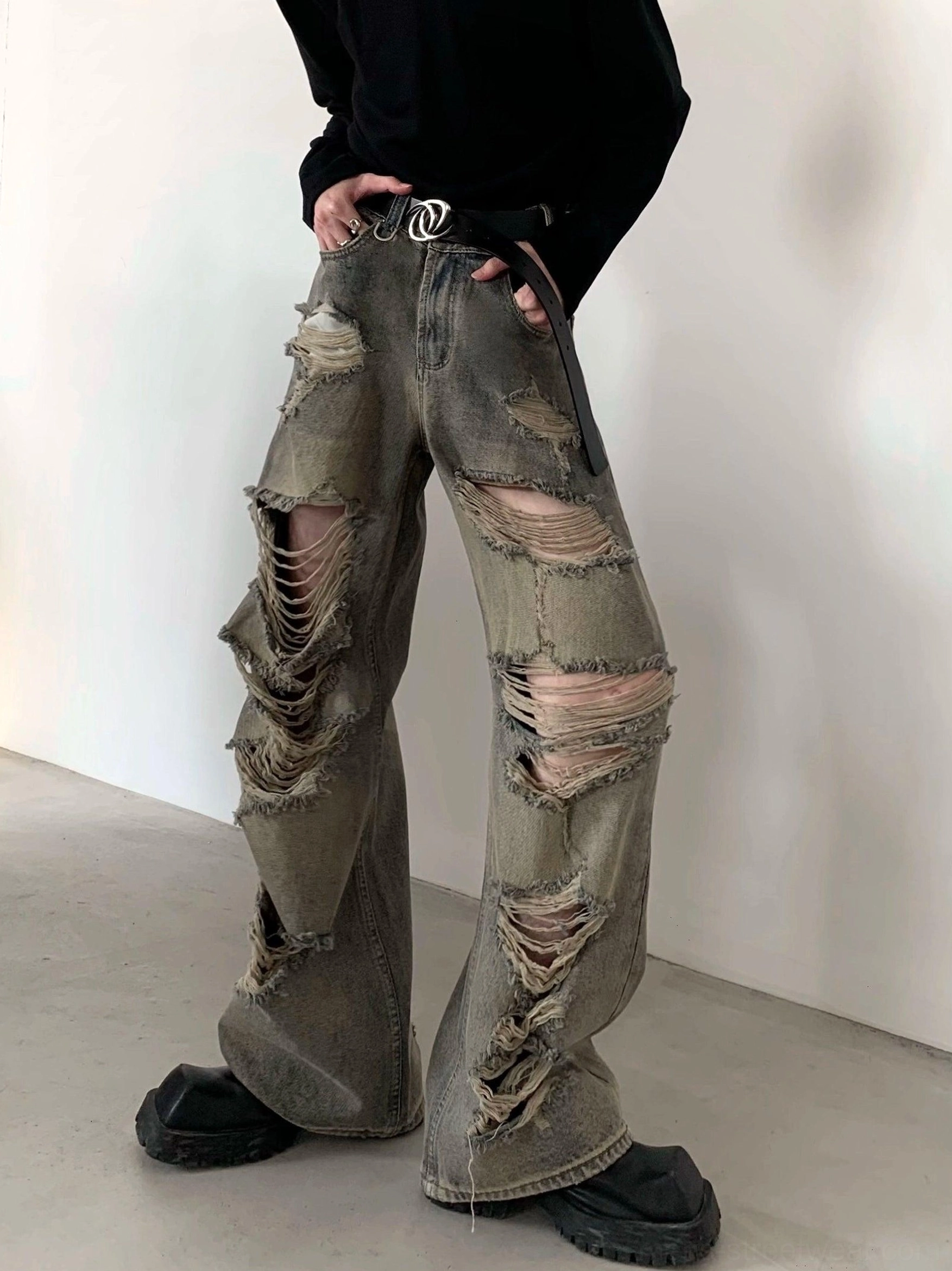 Front detail of faded distressed wide-leg denim cargo pants with shredded thigh panels, ripped knees, and loose fit