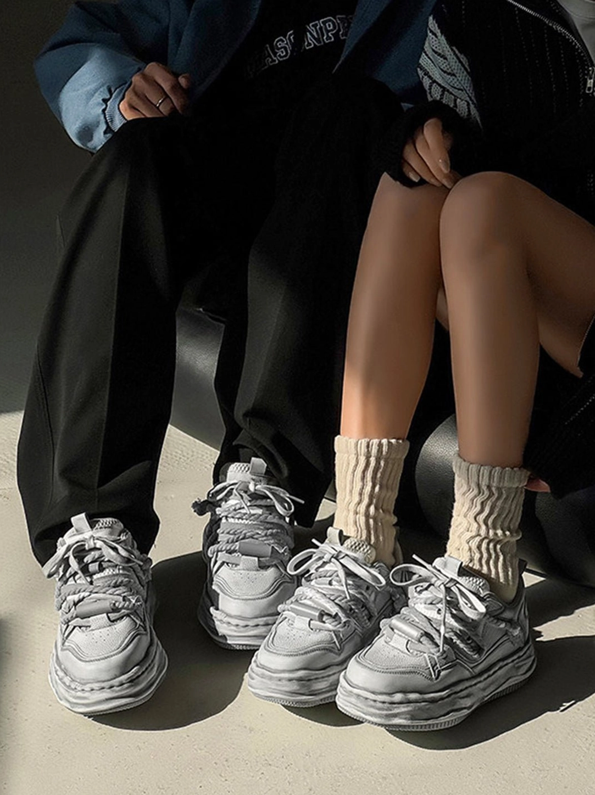 Two models wearing faded gray wavy platform sneakers with casual outfits, demonstrating the unisex streetwear fit