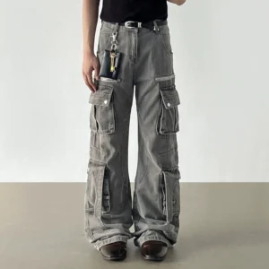Faded grey multi-pocket cargo denim jeans worn from the front featuring wide legs, utility pockets, and zipper accents